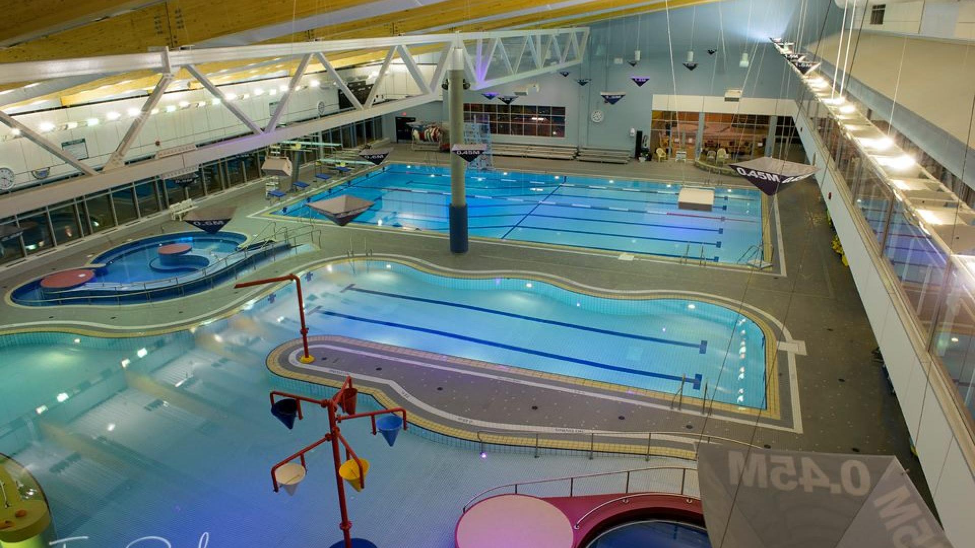 Indoor pool complex with multiple pools and bright overhead lighting.